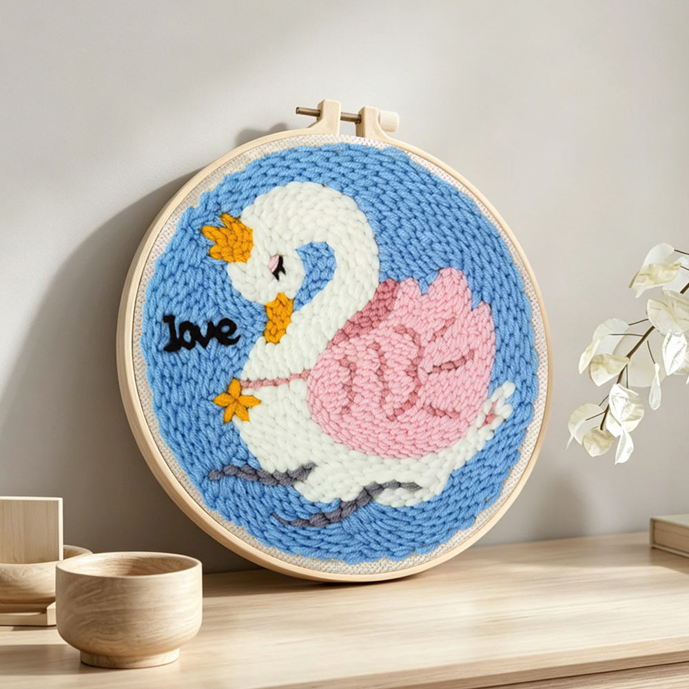 White swan with pink wings punch needle artwork displayed on a table