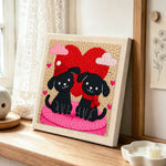 Winter black puppies with red heart punch needle artwork displayed on a table
