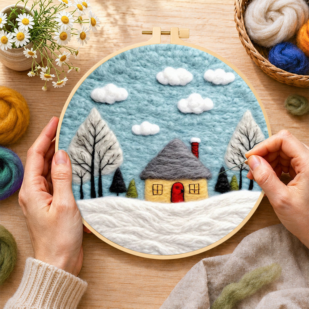 Creating the winter cabin and snow-covered trees wool painting by hand with a felting needle