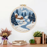 Finished winter cabin scene with snowy pine trees and blue river artwork displayed on a wall