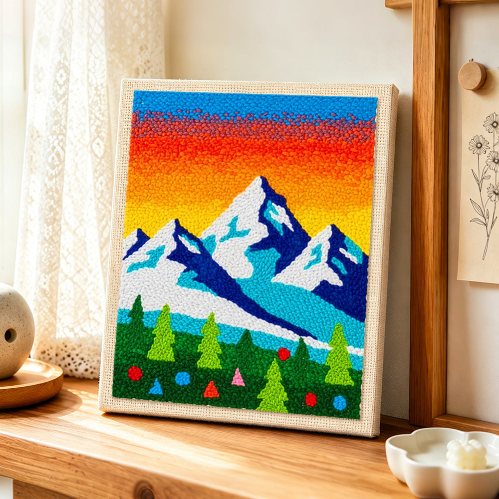 Winter mountains and pine forest punch needle artwork displayed on a table