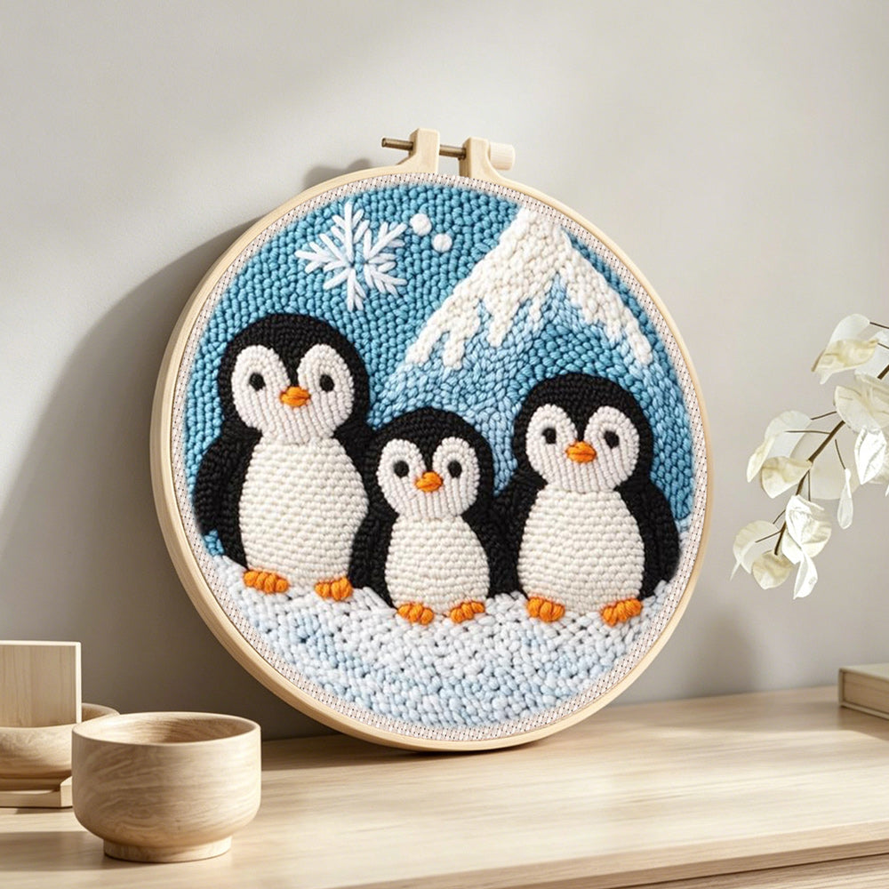 Winter penguin family and mountain punch needle artwork displayed on a table