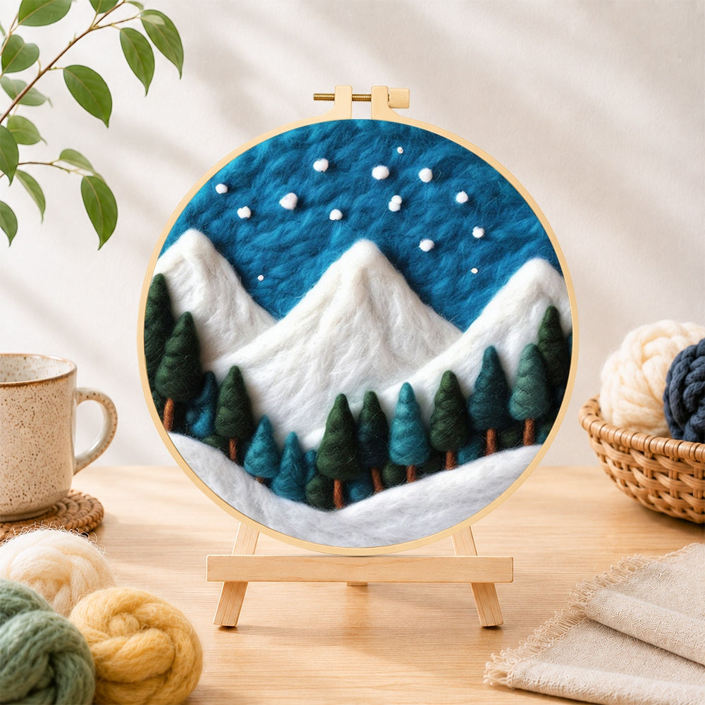 Finished winter snowy peaks and pine forest needle felting displayed on a wooden easel