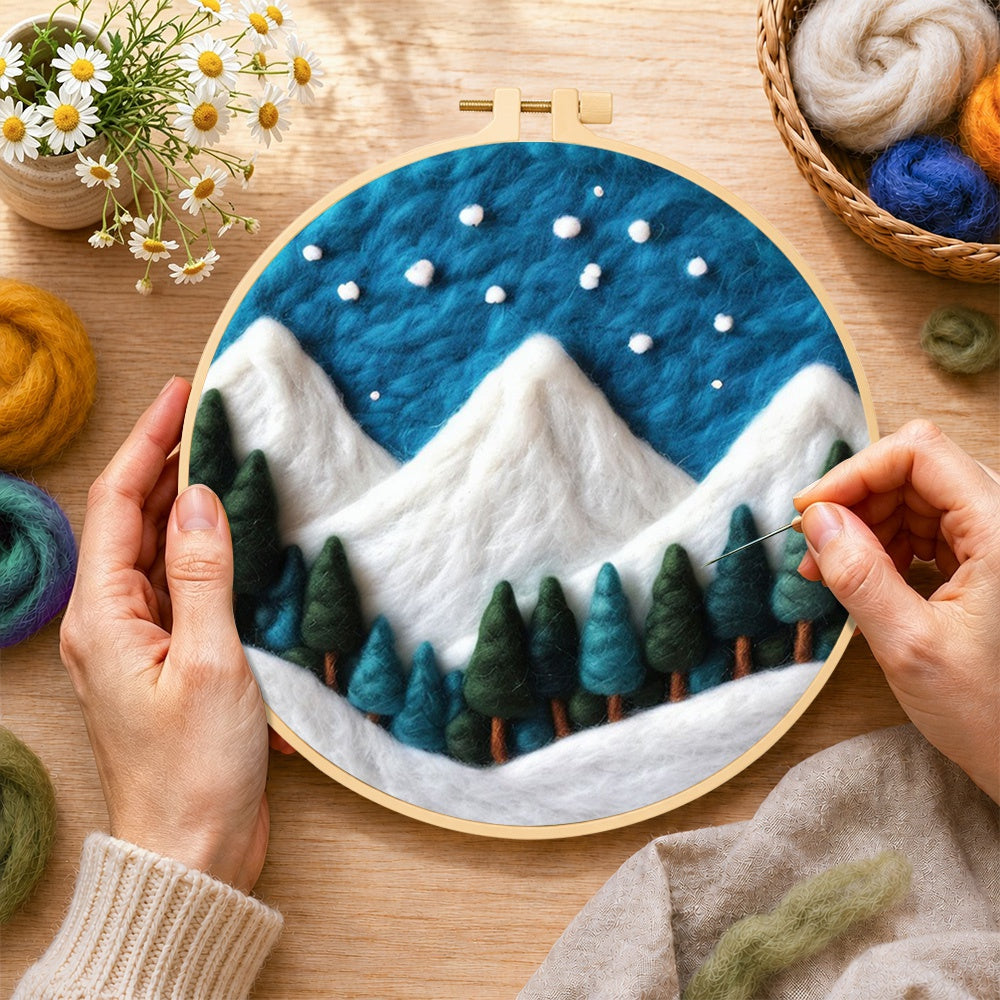 Creating the winter snowy peaks and pine forest wool painting by hand with a felting needle
