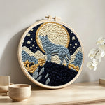 Wolf under moonlight punch needle artwork displayed on a table