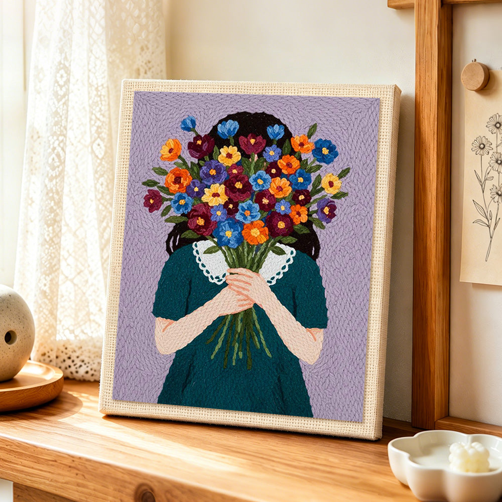 Woman holding flowers face hidde punch needle artwork displayed on a table