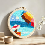 Woman on vacation at seaside punch needle artwork displayed on a table