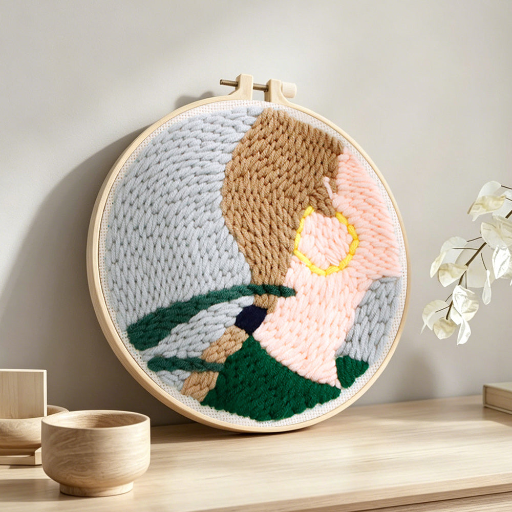 Woman wearing gold earrings punch needle artwork displayed on a table