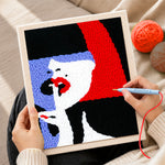 Creating handmade woman with red lips and bold hair punch needle artwork