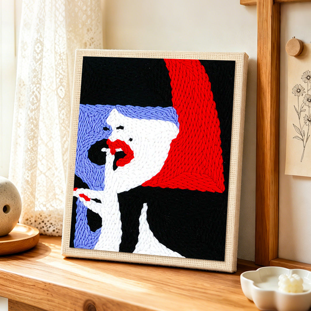 Woman with Red Lips and Bold Hair punch needle artwork displayed on a table
