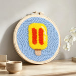 Yellow and red ice lolly punch needle artwork displayed on a table