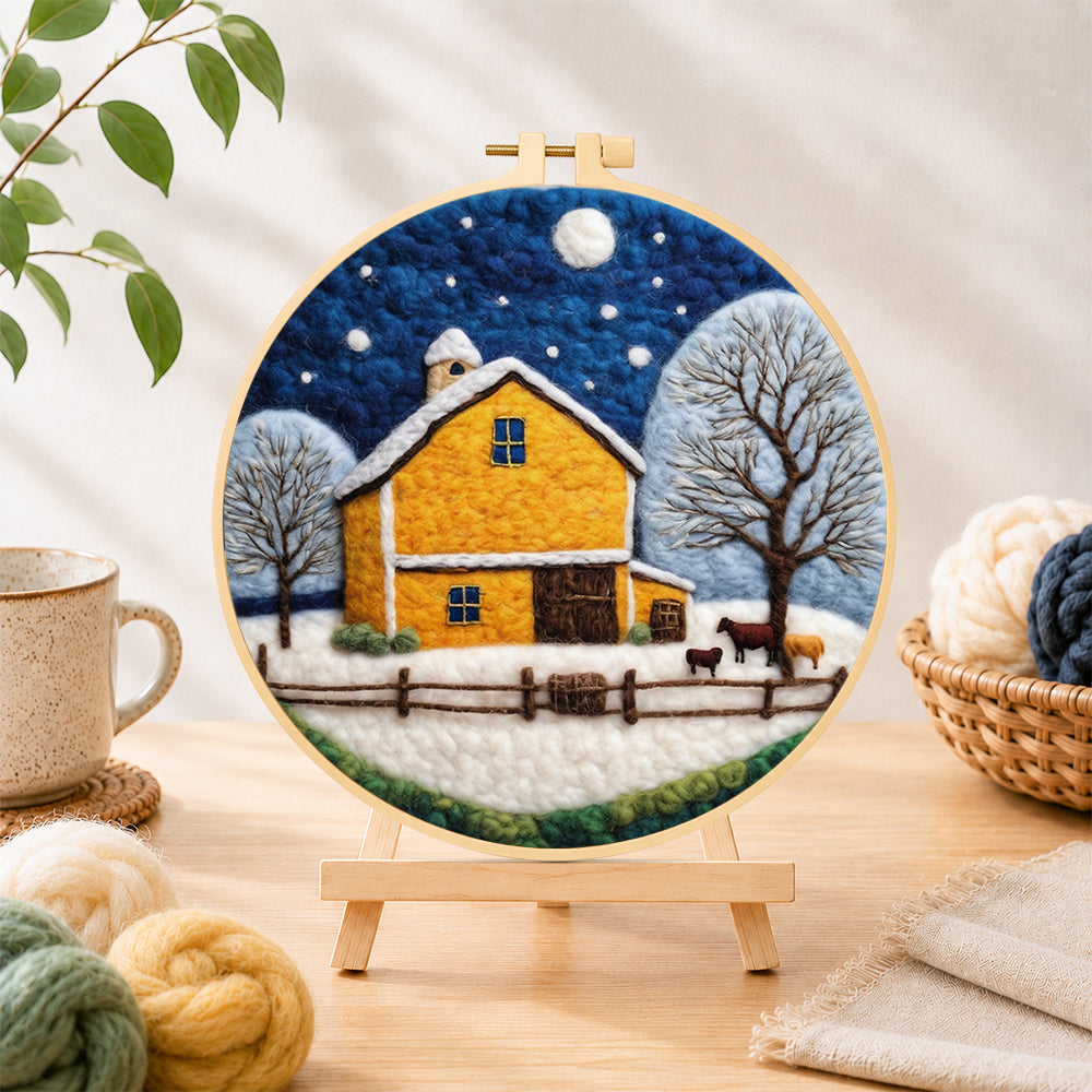 Finished yellow barn and white trees under the winter moon needle felting displayed on a wooden easel