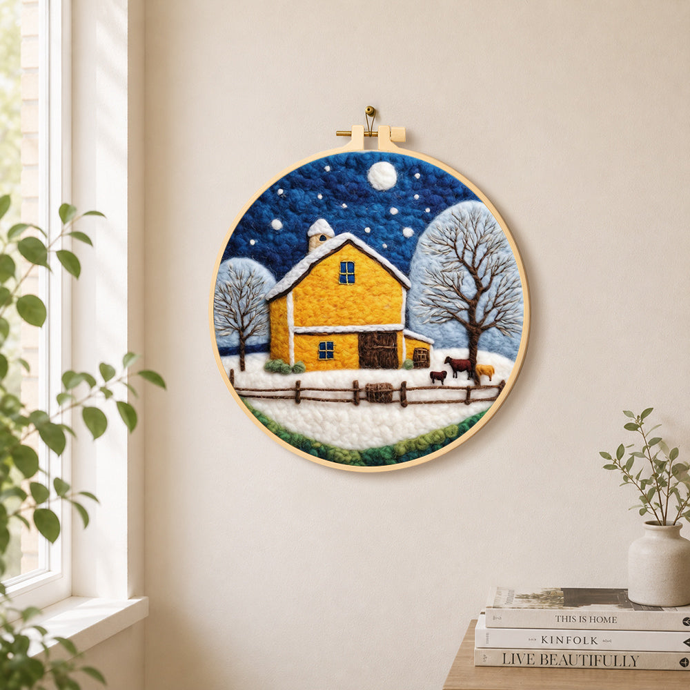 Yellow barn and white trees under the winter moon needle felt wall art displayed in a bright home interior