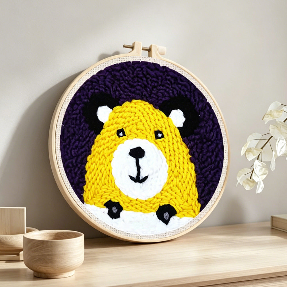 Yellow bear face punch needle artwork displayed on a table