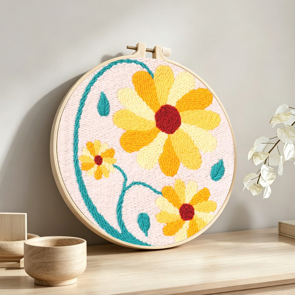 Yellow daisies with teal vines punch needle artwork displayed on a table
