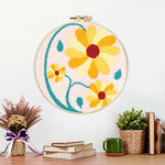 Finished yellow daisies with teal vines artwork displayed on a wall