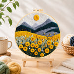 Finished yellow flower field with mountains needle felting displayed on a wooden easel