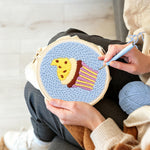 Creating handmade yellow frosting cupcake punch needle artwork