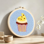 Yellow frosting cupcake punch needle artwork displayed on a table