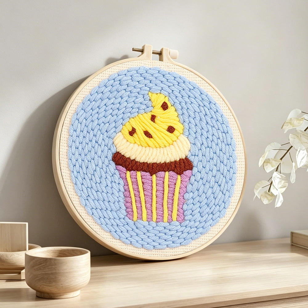Yellow frosting cupcake punch needle artwork displayed on a table