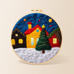 Yellow house and christmas tree in snowy village needle felting kit for beginners with a round wooden frame