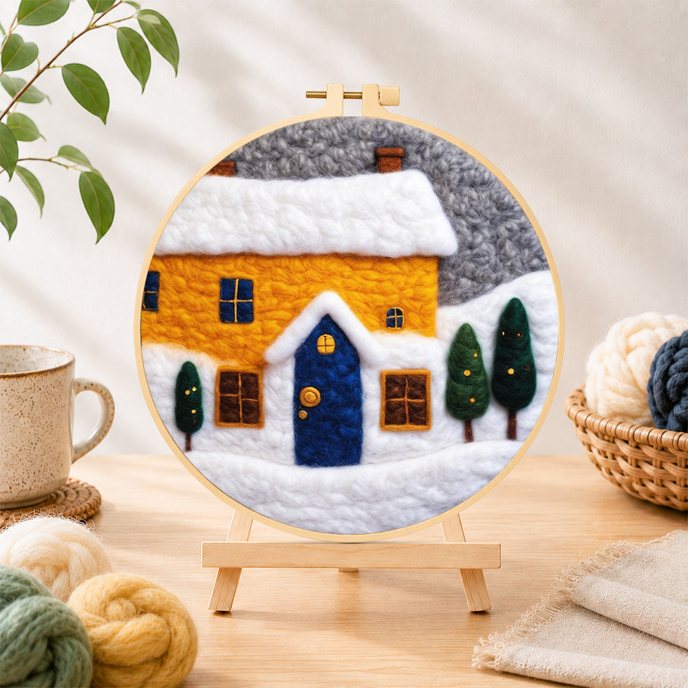 Finished yellow house and snowy ground needle felting displayed on a wooden easel