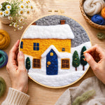 Creating the yellow house and snowy ground wool painting by hand with a felting needle