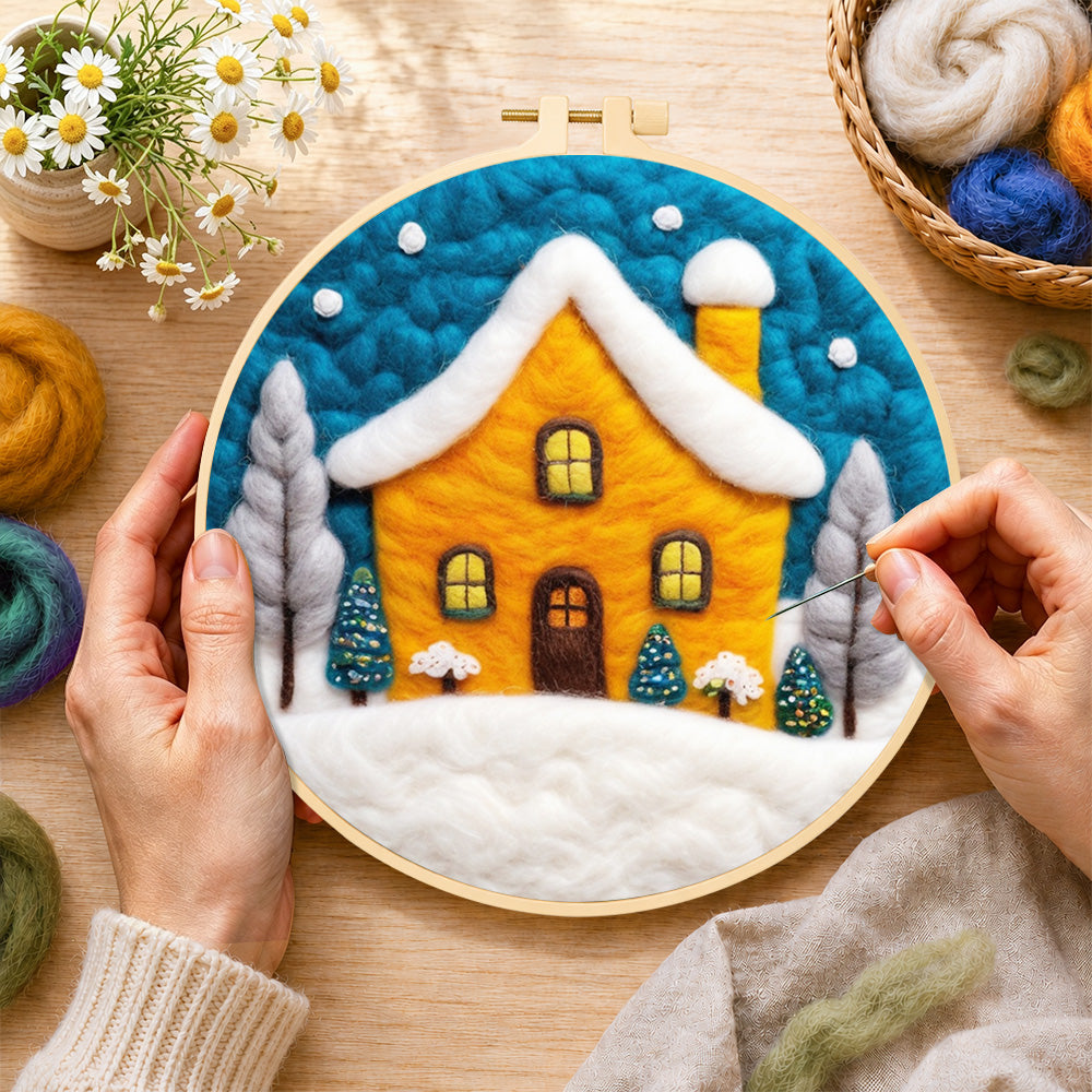 Creating the yellow house glowing in the blue snowy night wool painting by hand with a felting needle