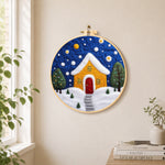 Yellow house with snowy path needle felt wall art displayed in a bright home interior