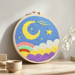 Yellow moon, colourful clouds and rainbow punch needle artwork displayed on a table