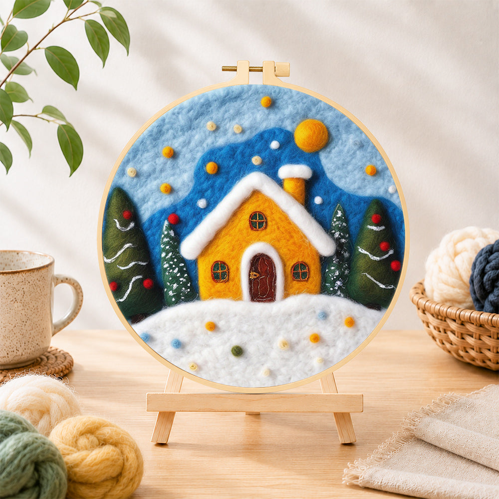 Finished yellow snowy cottage at christmas needle felting displayed on a wooden easel
