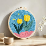Yellow tulips on pink hills punch needle artwork displayed on a table